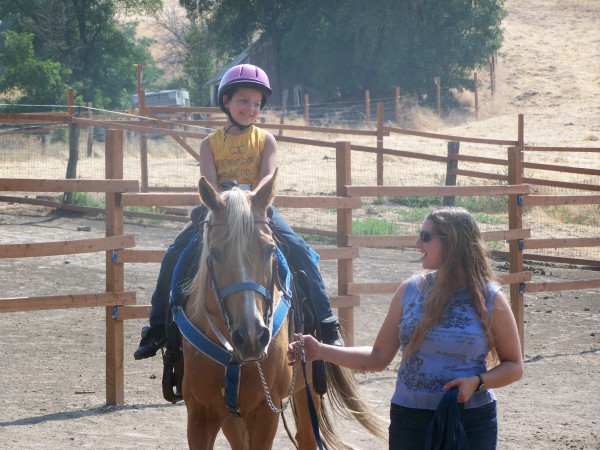Picture of a boy smiling during his first horse back ride.